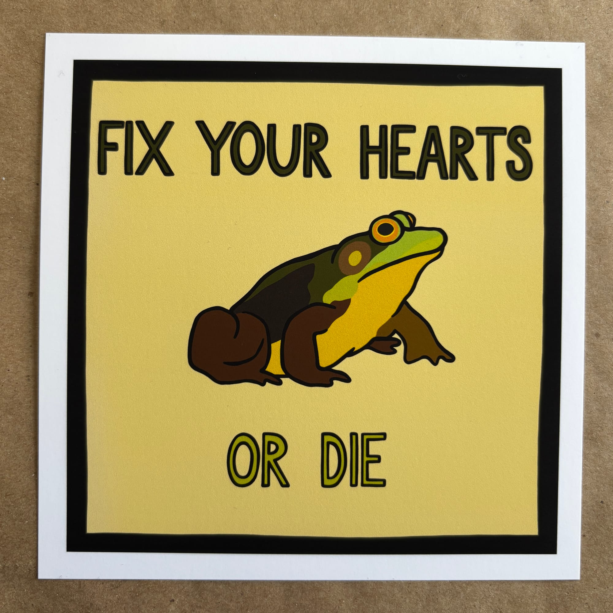 Original art by AnneArchy of a frog with hand lettering of the words "fix your hearts or die.”