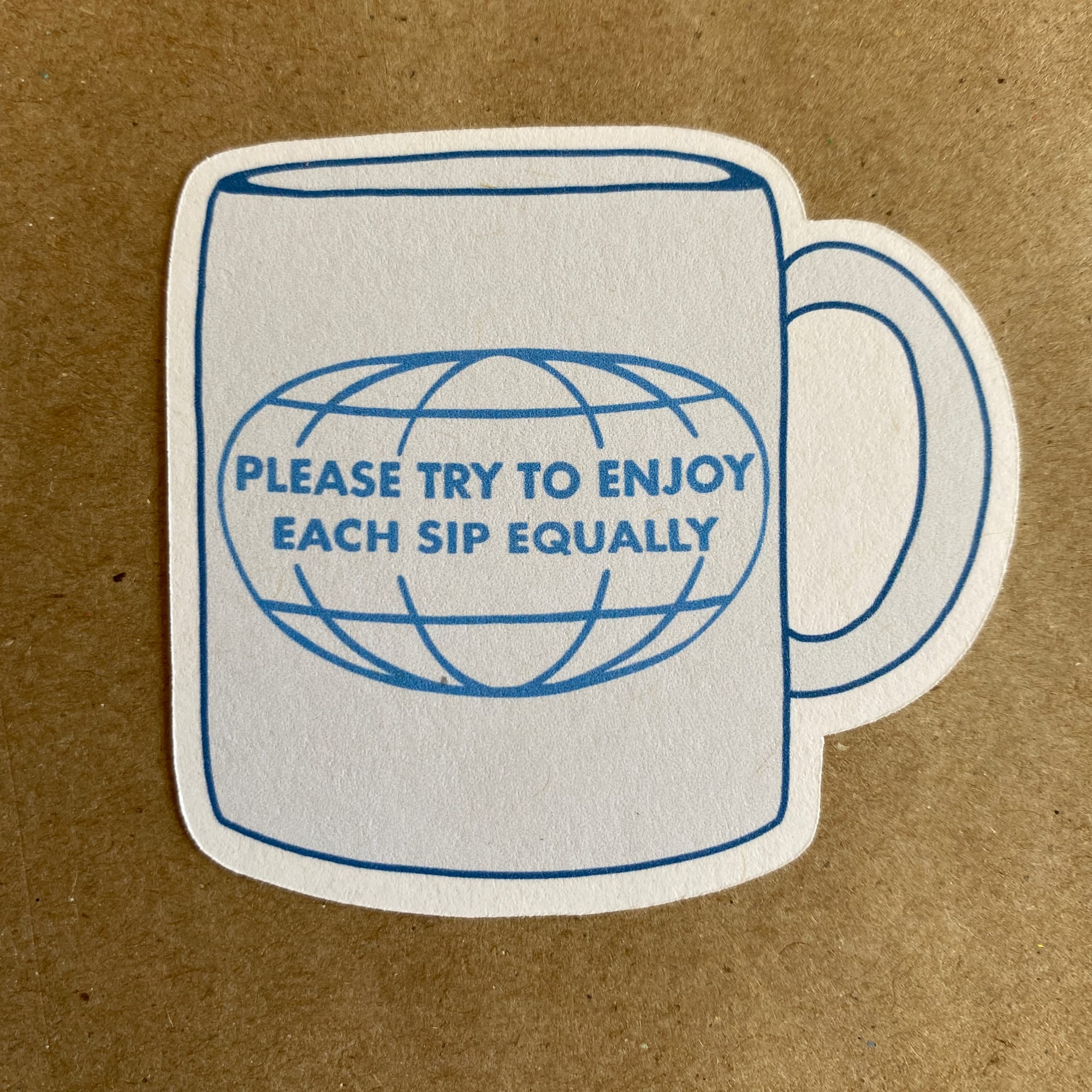 A paper sticker of original art by AnneArchy of a mug with hand lettering of the words "try to enjoy each sip equally."