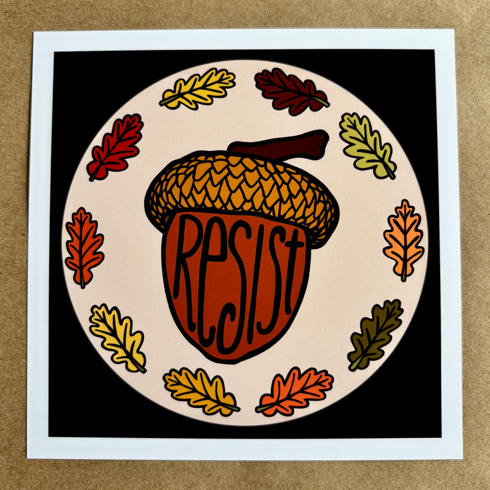 original art by AnneArchy depicting an acorn surrounded by oak leaves, with hand lettering of the word "resist"