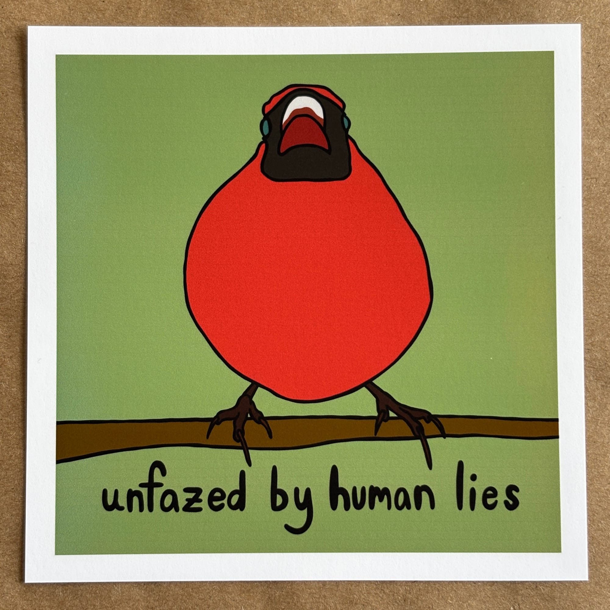 original art by AnneArchy of a plump red cardinal perched on a branch with hand-lettering of the words "unfazed by human lies."